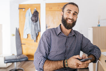 Portrait of smiling young man using cell phone at home - JRFF02178