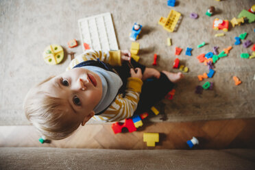 Overhead portrait of cute baby boy with toys sitting on carpet at home - CAVF57968