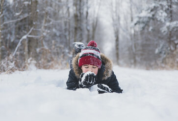 Unbekümmerter Junge auf verschneitem Feld liegend - CAVF57981