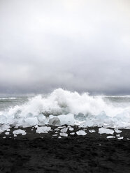 Idyllic view of waves splashing on glaciers at beach against sky - CAVF57985