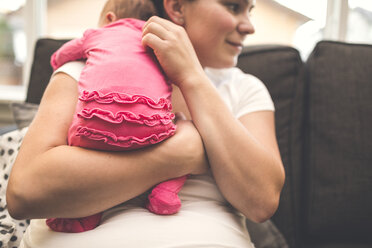 Mutter trägt ihre neugeborene Tochter auf dem Sofa zu Hause - CAVF58013
