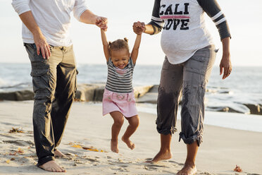 Tiefschnitt von Eltern, die mit ihrer Tochter am Strand bei Sonnenuntergang spielen - CAVF58028