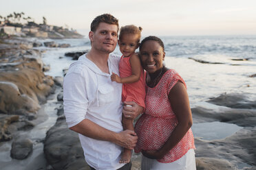 Portrait of happy parents with daughter at beach during sunset - CAVF58040