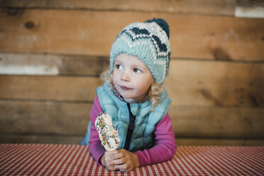 Cute girl looking away while holding ice cream at table - CAVF58087