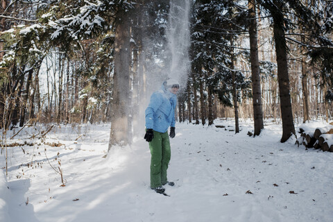 Mann steht auf einem schneebedeckten Feld im Wald, lizenzfreies Stockfoto