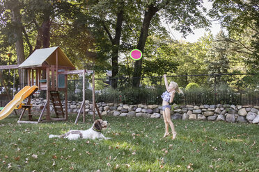 Verspieltes Mädchen wirft Frisbee mit Hund auf Spielplatz - CAVF58101