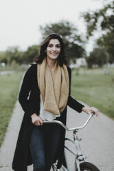 Porträt einer lächelnden Frau mit Fahrrad im Park - CAVF58163