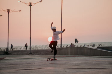 Unbeschwerter Mann beim Skateboardfahren auf dem Fußweg gegen den klaren Himmel bei Sonnenuntergang in voller Länge - CAVF58179