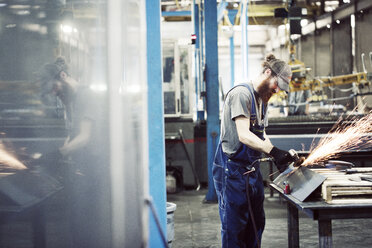 Arbeiter mit Latzhose bei der Benutzung einer Schweißmaschine in einem Stahlwerk - CAVF58202