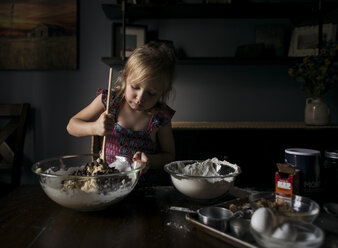 Girl mixing batter in bowl on table at home - CAVF58211