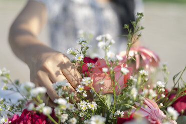 Mittelteil einer Frau, die Blumen zu einem Strauß arrangiert - CAVF58224