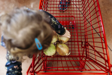 Draufsicht auf ein Mädchen, das im Supermarkt Gemüse in den Einkaufswagen legt - CAVF58238