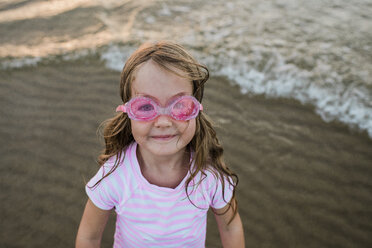 Porträt eines süßen Mädchens, das eine Schwimmbrille trägt und am Strand steht - CAVF58265