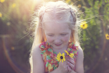 Nettes Mädchen mit gelben Blumen auf einem Feld an einem sonnigen Tag - CAVF58274