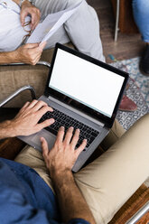 Close-up of businessmen with laptop and documents sitting in armchairs - GIOF04988