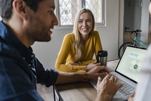 Businesswoman smiling at businessman during a meeting in office - GIOF05015