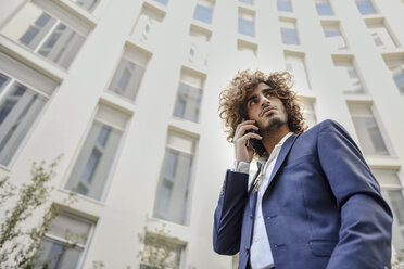 Porträt eines jungen Geschäftsmannes mit lockigem Haar am Telefon - JSMF00648