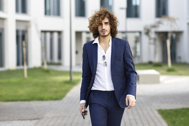 Portrait of young fashionable businessman with curly hair wearing blue suit - JSMF00658