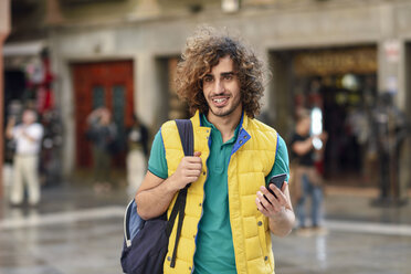 Spanien, Granada, Porträt eines lächelnden jungen Touristen mit Rucksack, der die Stadt entdeckt - JSMF00680
