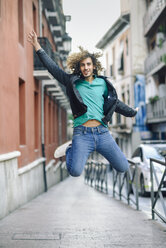 Portrait of smiling young man jumping in the air outdoors - JSMF00693
