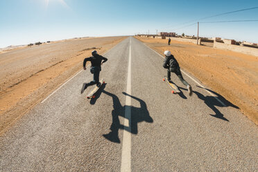 Volle Länge Rückansicht von Freunden Skateboarding auf der Straße gegen den Himmel während des sonnigen Tages - CAVF58294