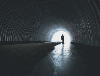 Rückansicht einer Silhouette eines Jungen im nassen Tunnel - CAVF58303