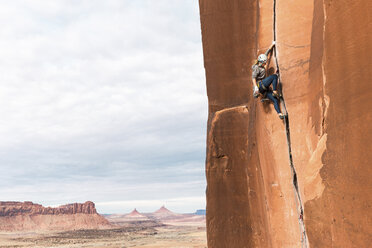 Side view of female hiker rock climbing against sky - CAVF58329