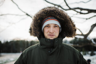 Porträt eines Mannes in warmer Kleidung, der im Winter vor dem Himmel steht - CAVF58345
