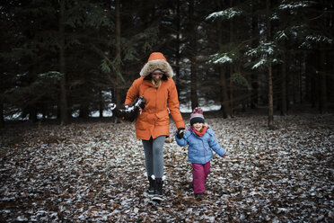 Mother and daughter in warm clothing walking at forest during winter - CAVF58347