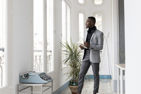 Young businessman standing in office looking out of the window stock photo