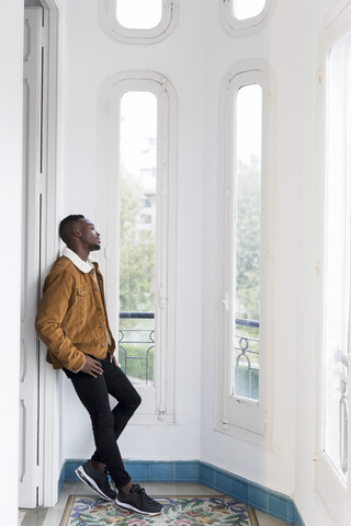 Junger Mann schaut aus dem Fenster, lizenzfreies Stockfoto