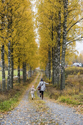 Finnland, Kuopio, Rückenansicht von Mutter und kleiner Tochter, die im Herbst nebeneinander laufen - PSIF00186