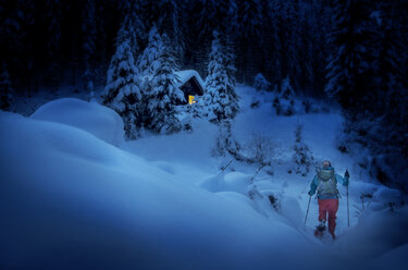 Austria, Salzburg State, snowshoeing, woman near hut at night - HHF05569