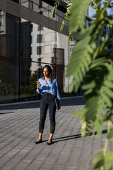 Businesswoman using smartphone, laptop bag - MAUF01848