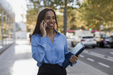 Businesswoman using smartphone, laptop bag - MAUF01857