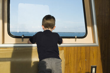 Rückansicht eines Jungen, der durch das Fenster schaut, während er in einem Boot fährt - CAVF58416