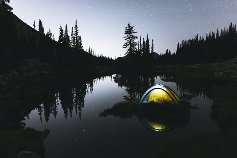 Beleuchtetes Zelt im See gegen den Himmel in der Abenddämmerung, lizenzfreies Stockfoto