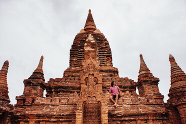 Mann sitzt auf buddhistischem Tempel gegen den Himmel - CAVF58431