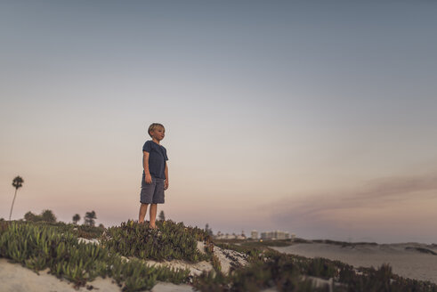 Junge in voller Länge auf Sand am Strand stehend gegen den Himmel bei Sonnenuntergang - CAVF58463