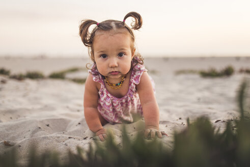 Porträt eines niedlichen kleinen Mädchens, das am Strand auf dem Sand krabbelt - CAVF58464