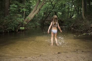 Rückansicht eines Mädchens, das in einem See im Wald steht - CAVF58555