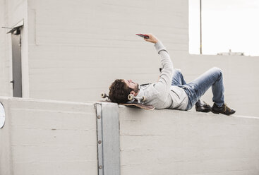 Mann nimmt Selfie in voller Länge, während er auf einer Stützmauer liegt - CAVF58580