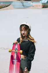 Hochformatiges Porträt einer Frau mit Skateboard im Park - CAVF58619