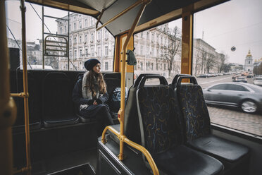 Nachdenkliche Frau, die durch das Fenster schaut, während sie im Trolleybus reist - CAVF58626