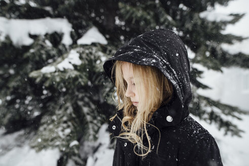Seitenansicht eines Mädchens, das an einem schneebedeckten Baum im Hof steht - CAVF58682