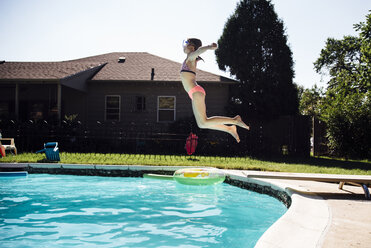 Seitenansicht eines Mädchens mit ausgestreckten Armen, das in ein Schwimmbecken springt - CAVF58683