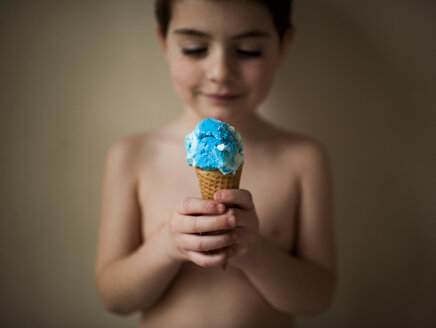 Hemdloser Junge hält Eiscreme, während er zu Hause an der Wand steht - CAVF58692