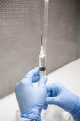 Cropped hands of dentist examining medicine in syringe - CAVF58699