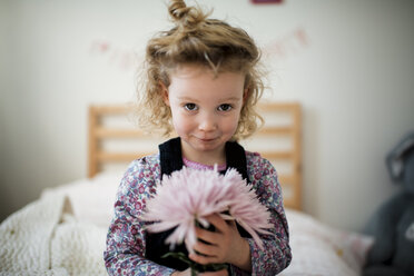 Porträt eines niedlichen Mädchens mit Gerbera im Schlafzimmer - CAVF58719