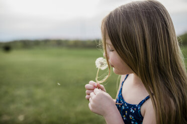 Side view of girl with dandelion flower on grassy field - CAVF58722